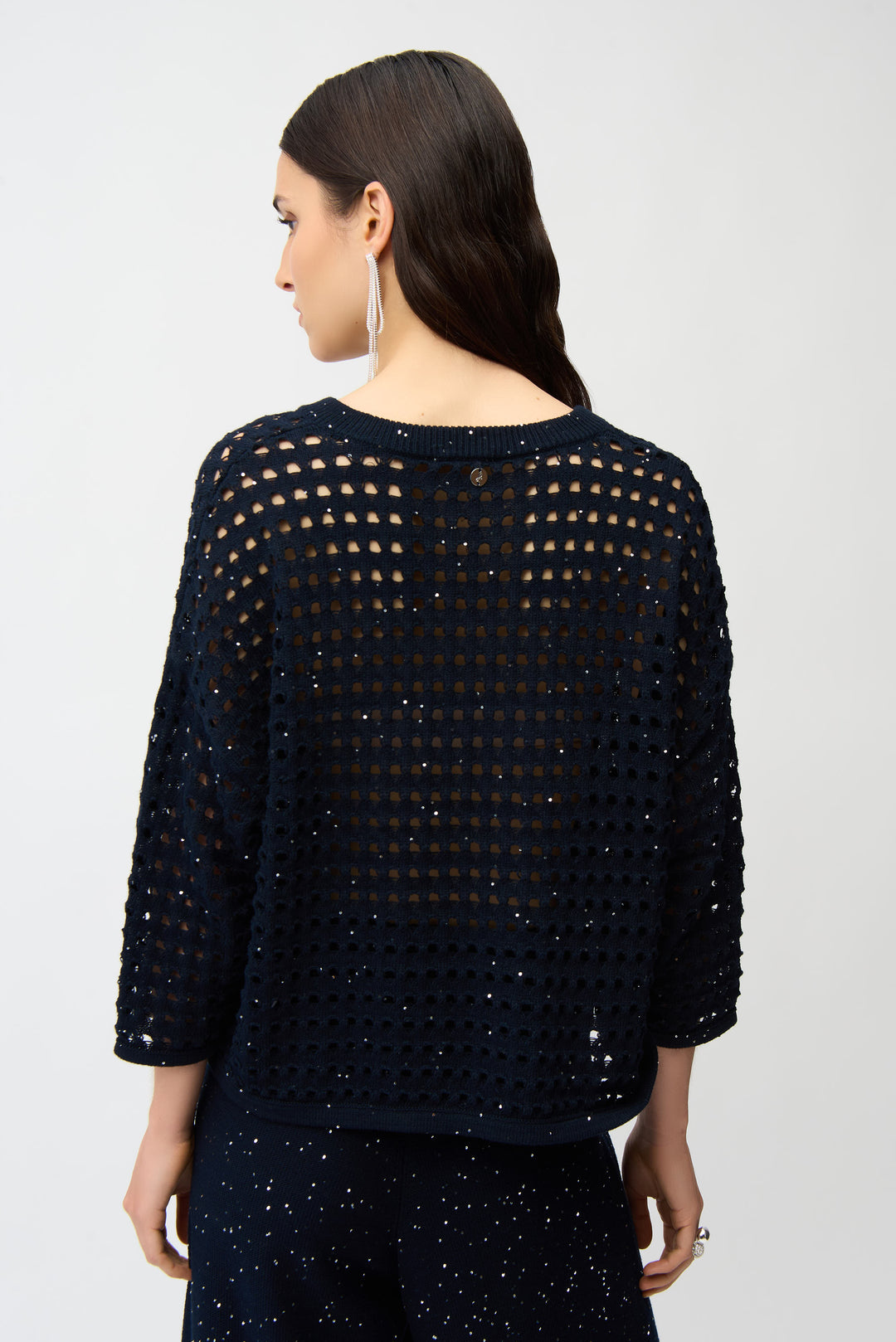 Woman wearing a dark blue knit sweater top with a textured pattern on a white background