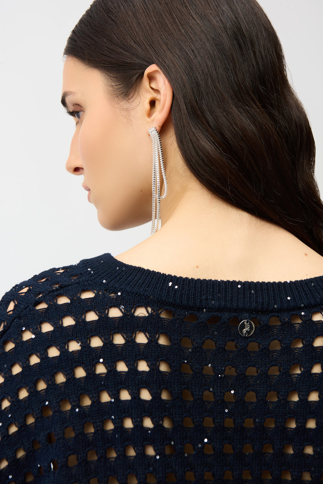 Woman wearing a navy blue open-knit cardigan with a plain background