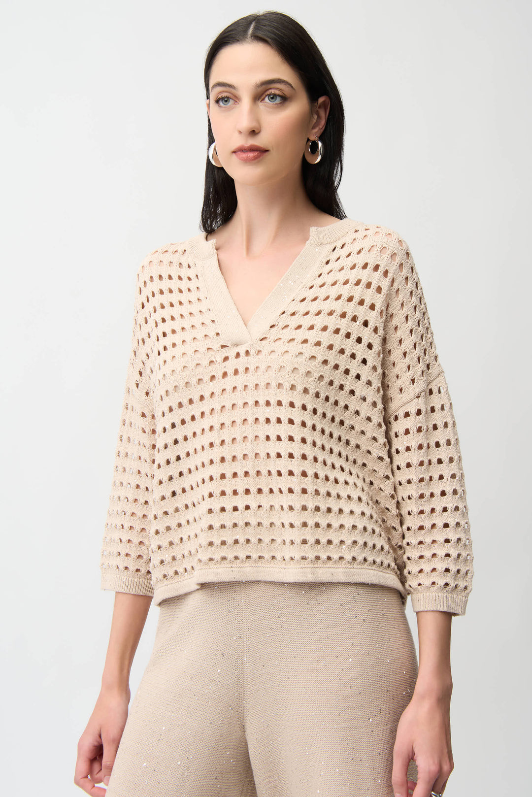 Woman wearing a beige crochet top against a white background
