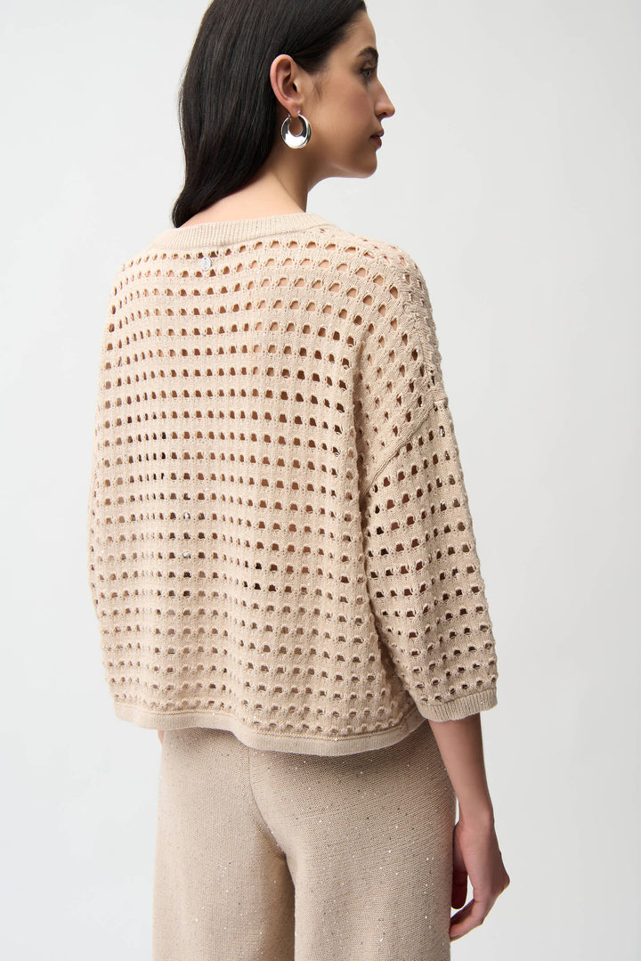 Woman wearing a beige crochet sweater top against a white background