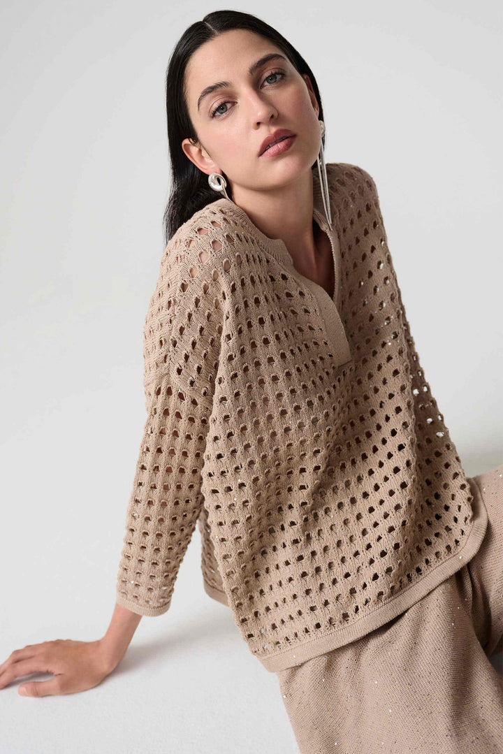 Woman wearing a beige crochet pullover sweater top against a plain background