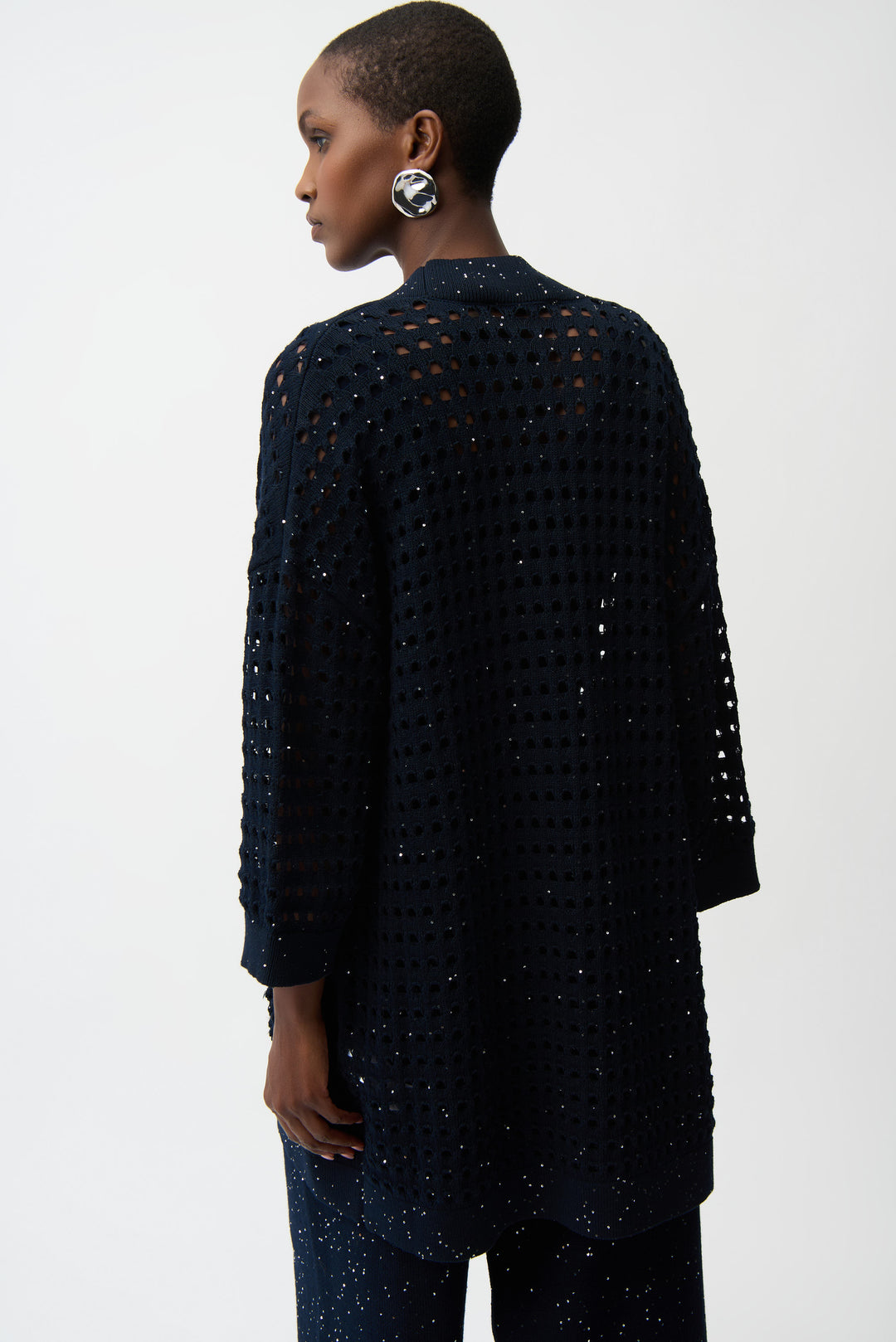 Person wearing a black textured cardigan on a white background