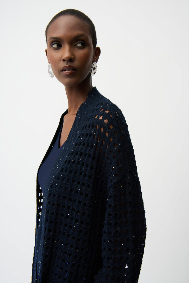 Woman wearing a dark blue, intricately patterned dress against a white background