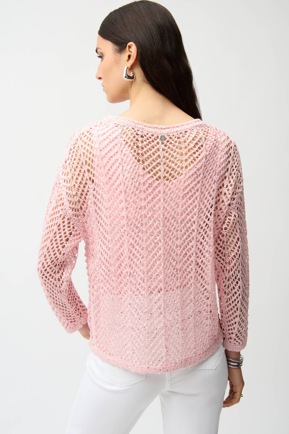 Woman wearing a pink knitted crochet mesh sweater on a white background