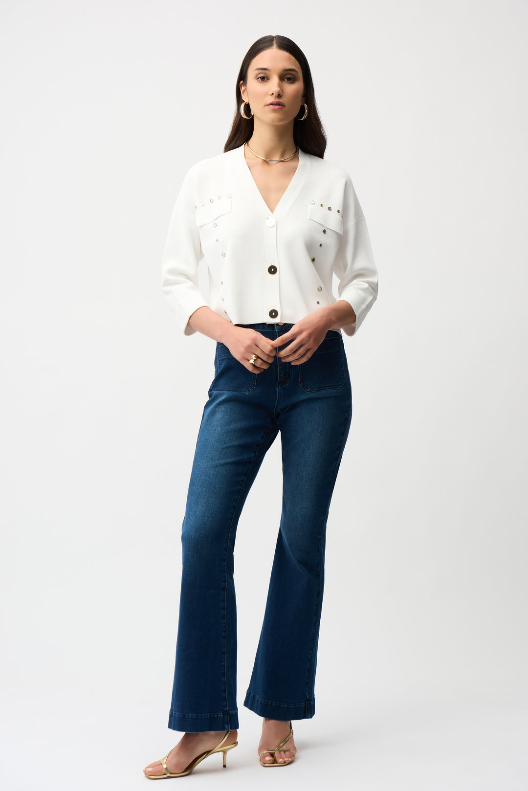 Woman wearing a white button cardigan and blue jeans on a white background