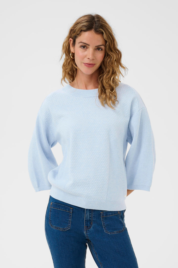 Woman wearing a light blue sweater and blue jeans on a white background