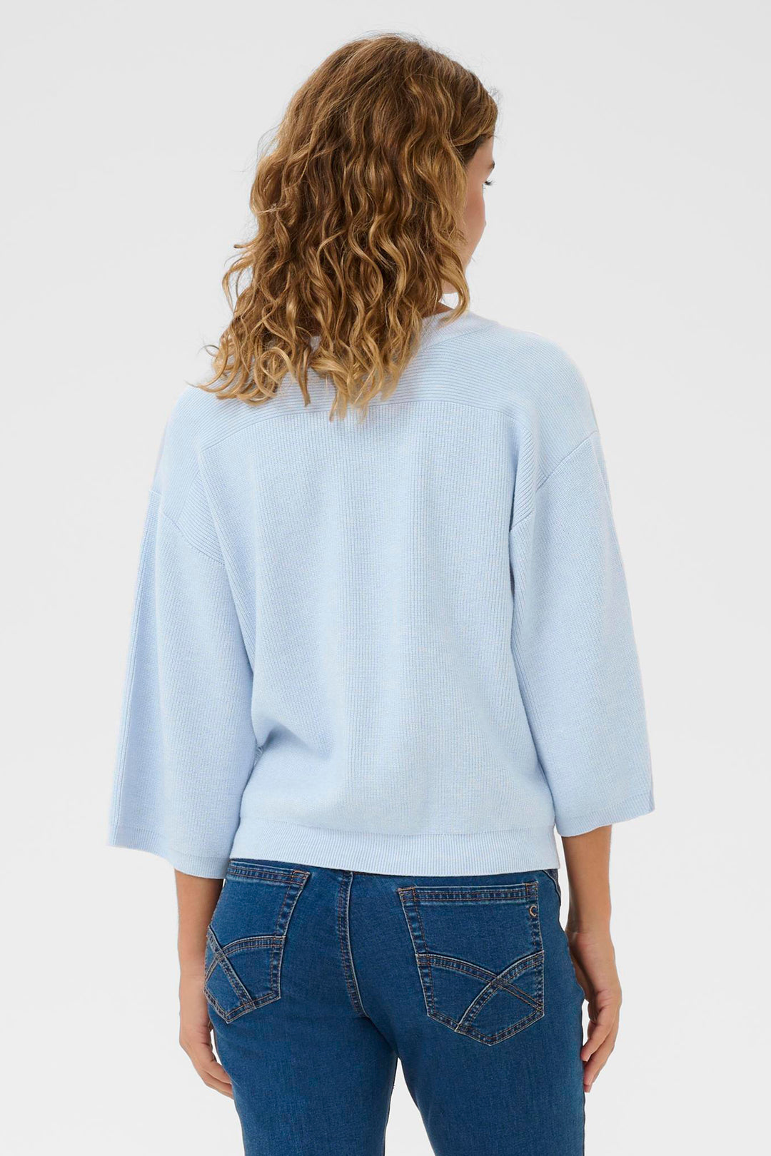 Woman wearing a light blue sweater and blue jeans on a white background