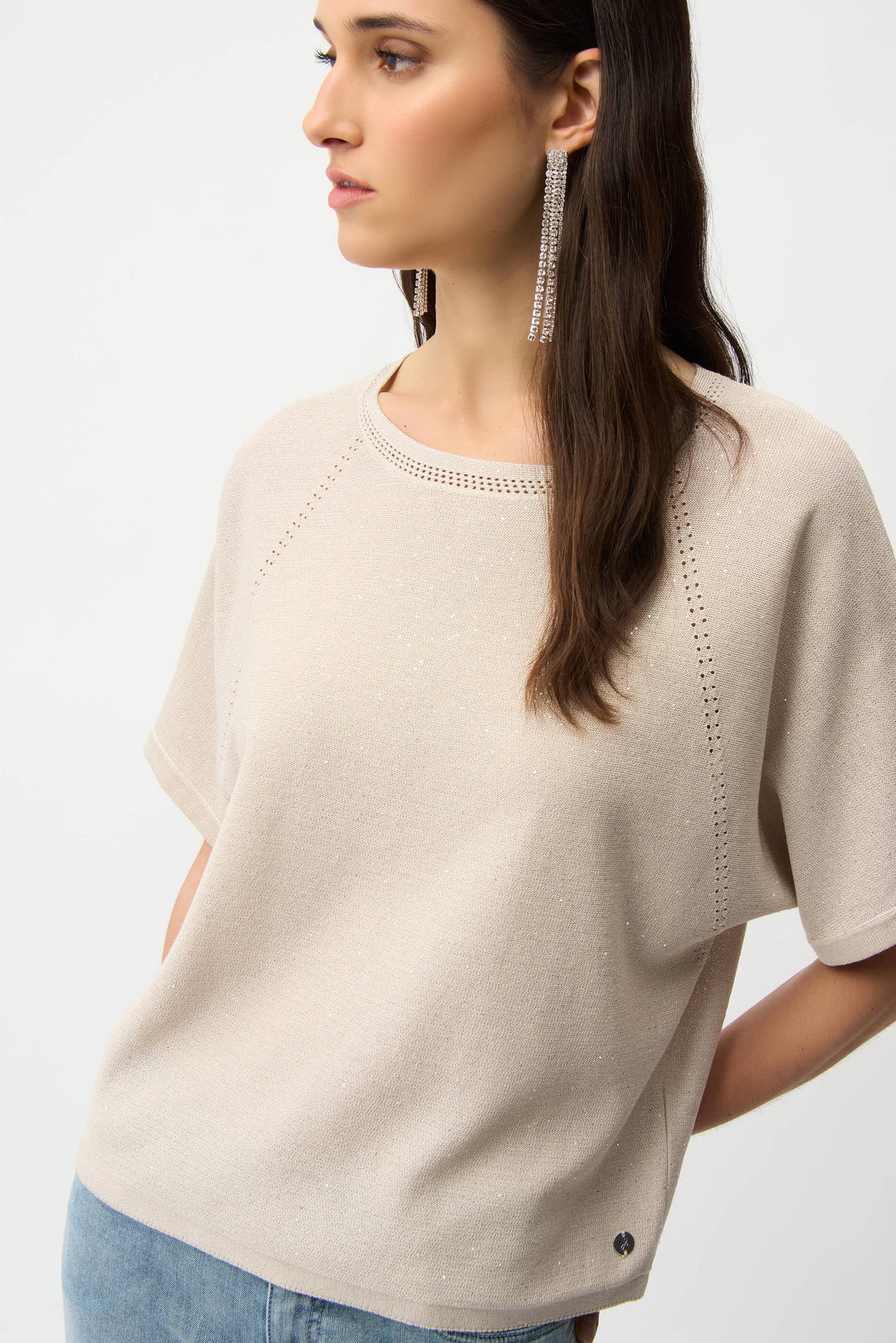 Woman wearing a beige sweater with a plain background