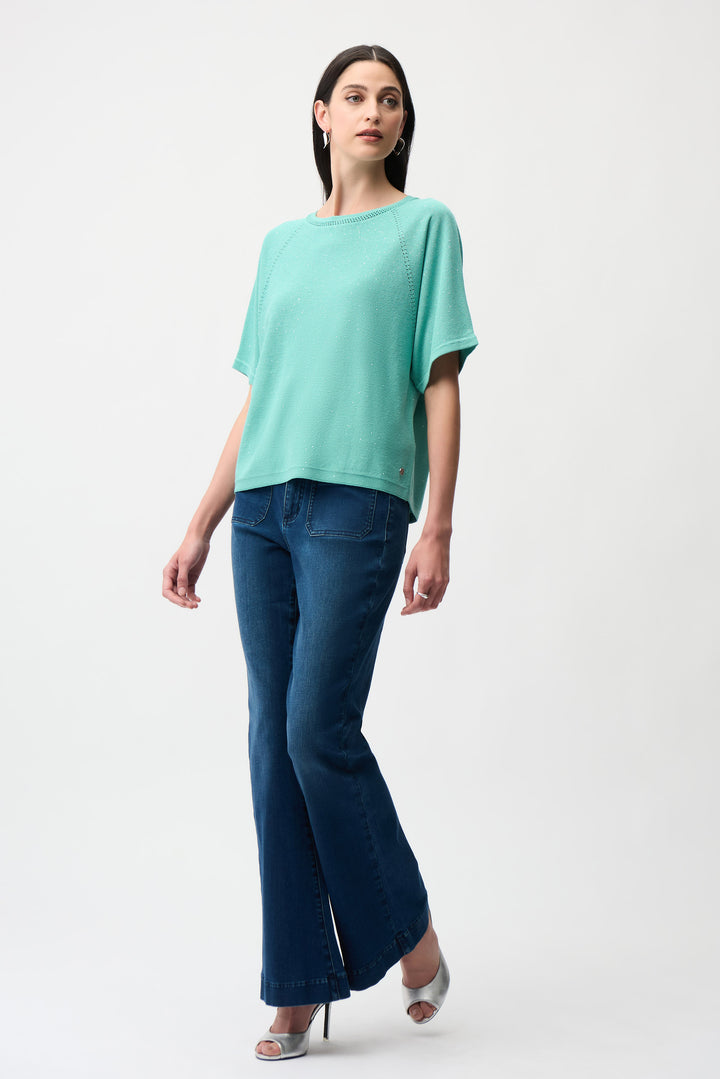 Woman wearing a teal top and blue pants on a white background