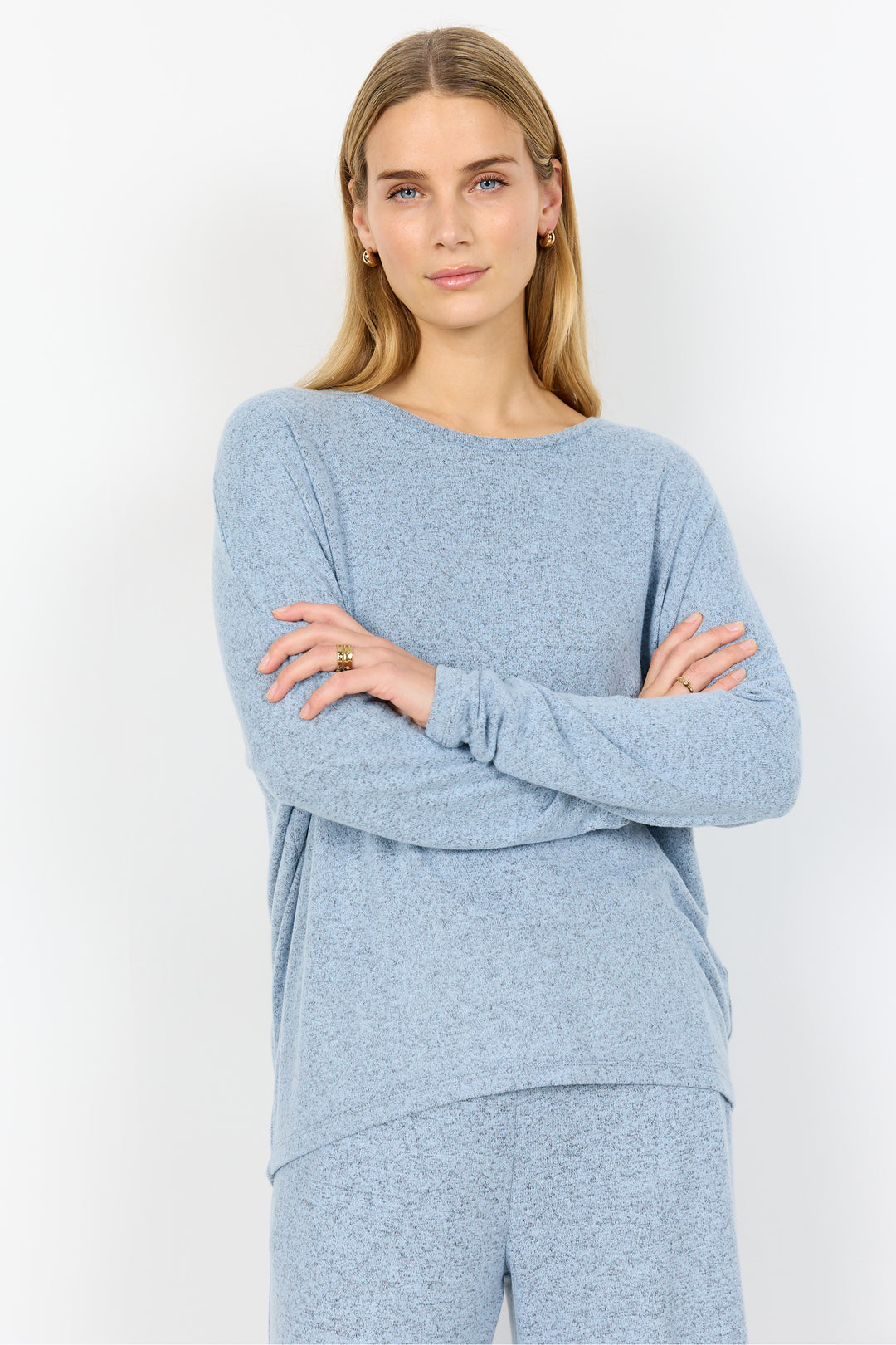 Woman wearing a light blue sweater and pants against a white background