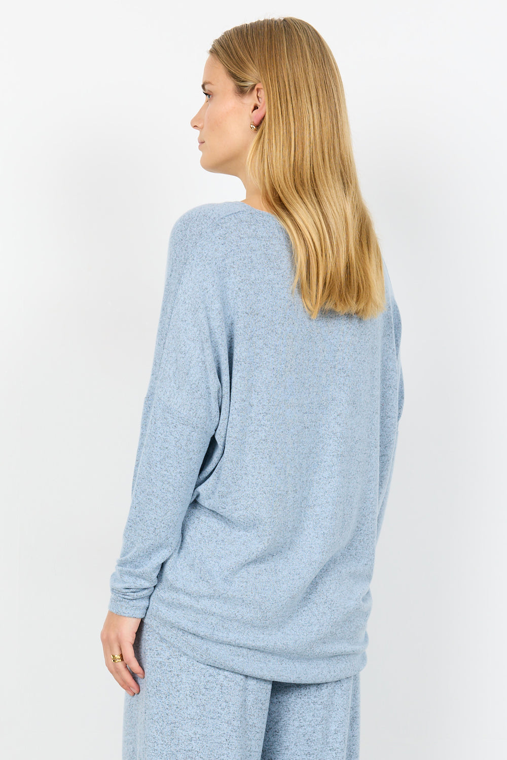 Woman wearing a light blue sweater and pants on a white background