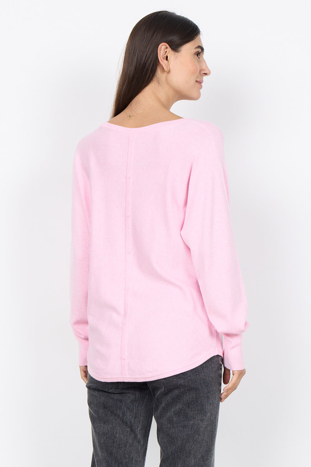 Woman wearing a pink sweater and gray pants on a white background