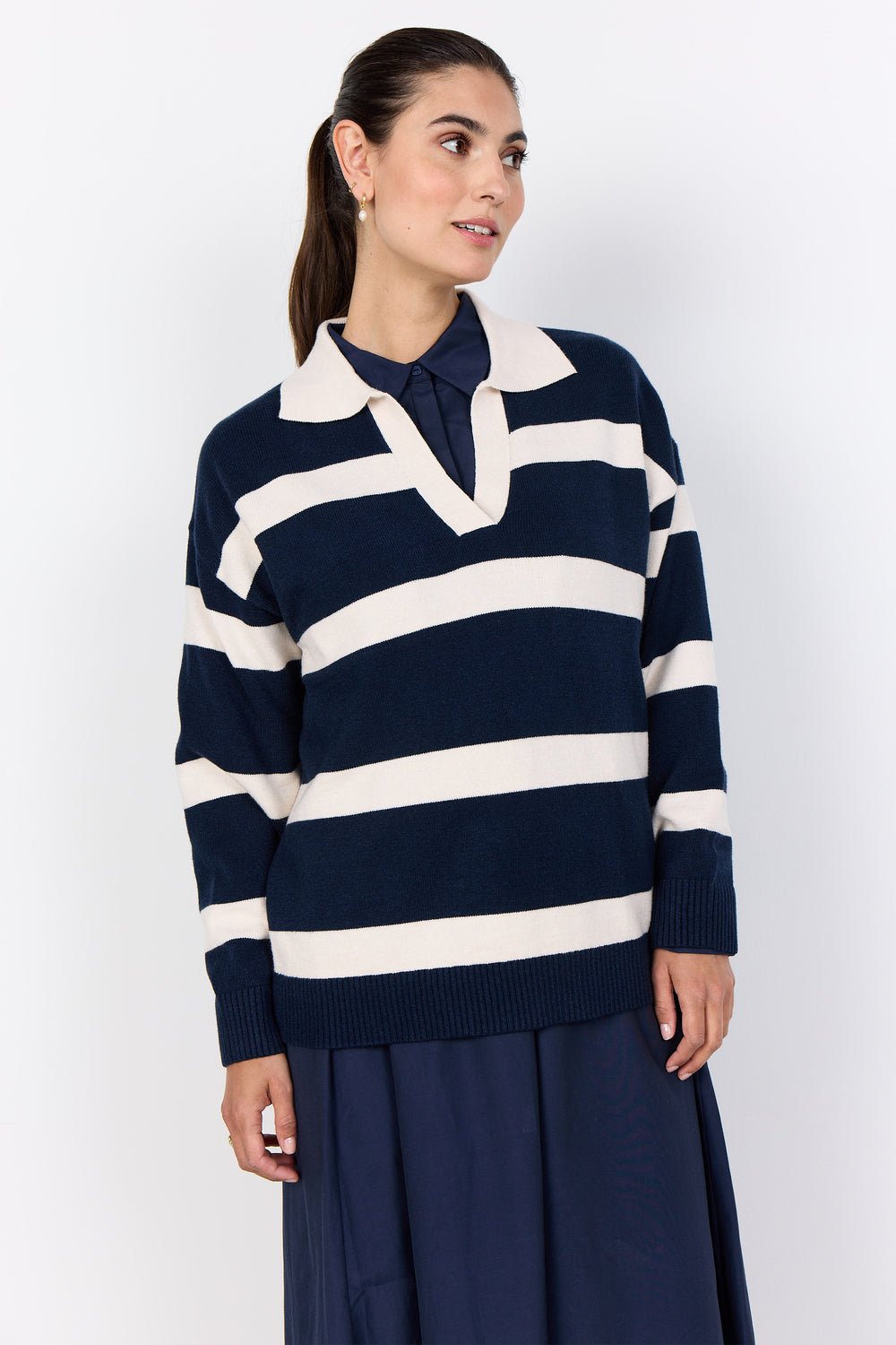 Woman wearing a navy and white striped sweater with a collar against a white background