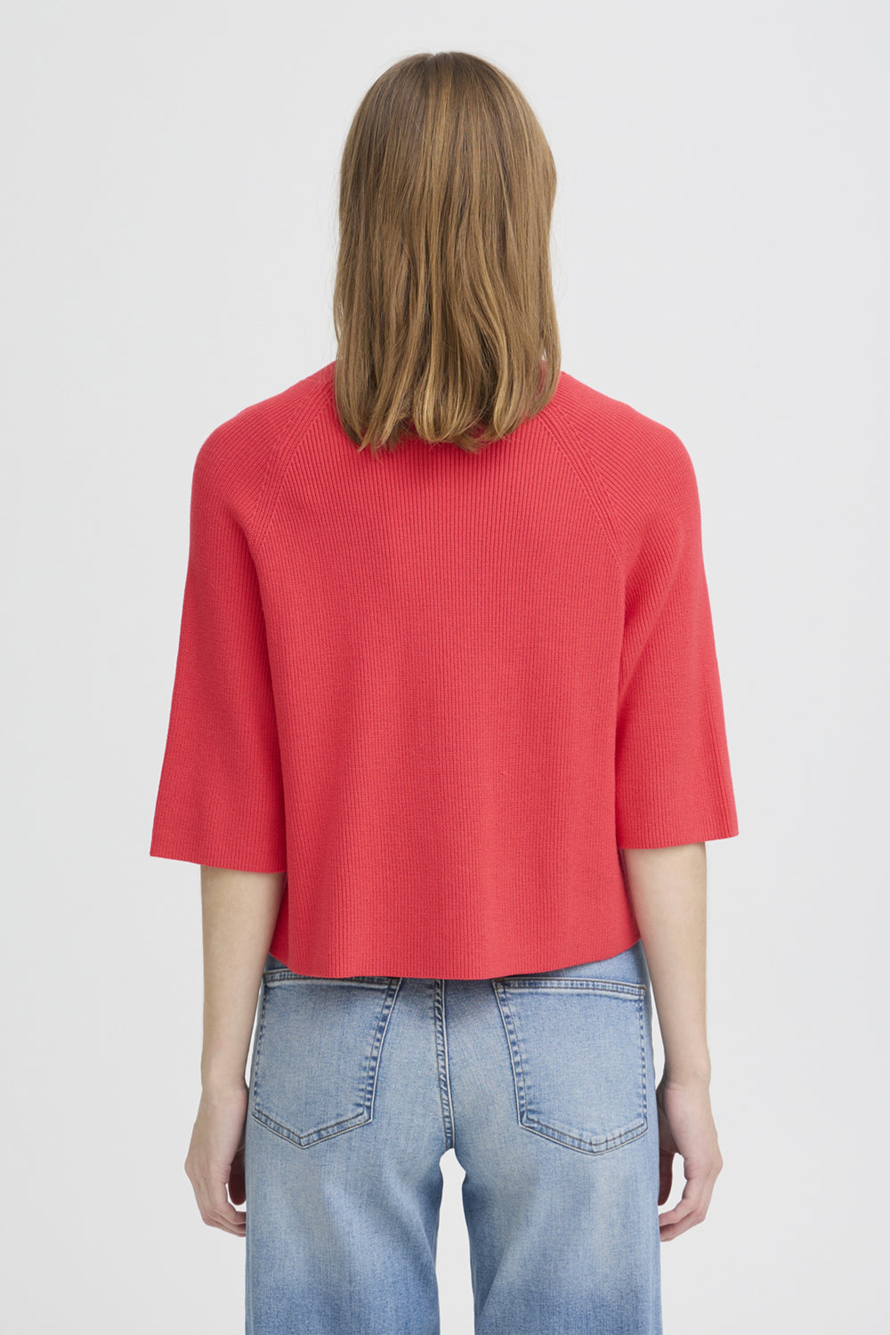 Person wearing a red top and blue jeans on a white background