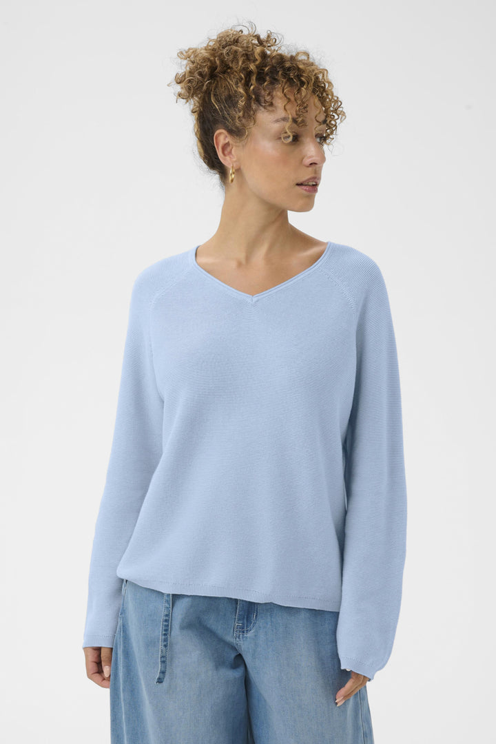 Woman wearing a light blue sweater and jeans on a white background