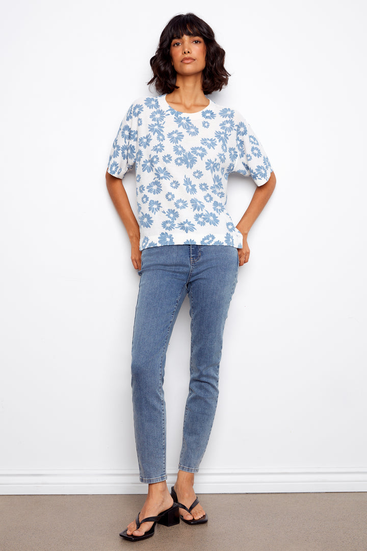 Woman wearing a floral sweater and jeans against a white background