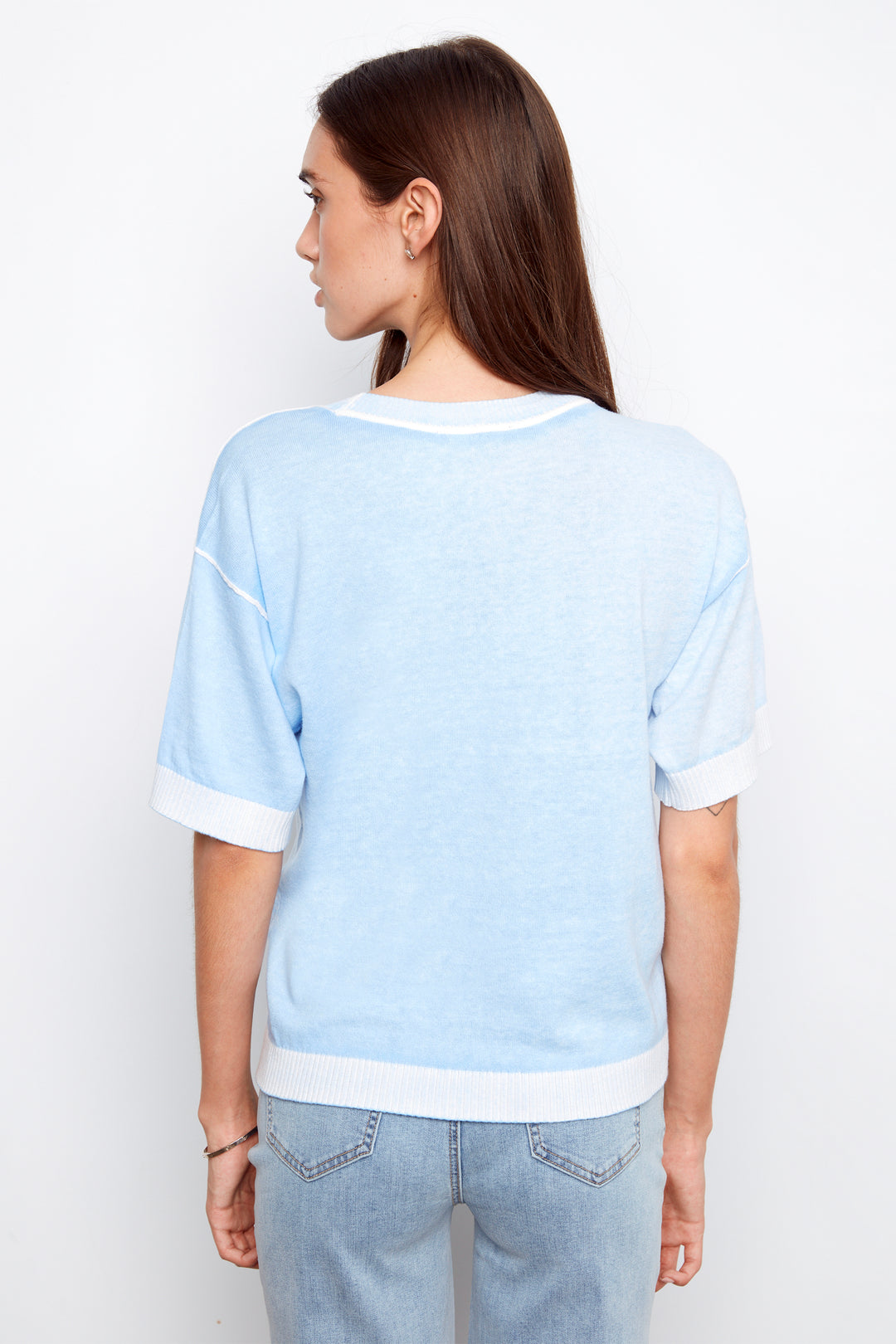 Woman wearing a light blue sweater and jeans against a white background