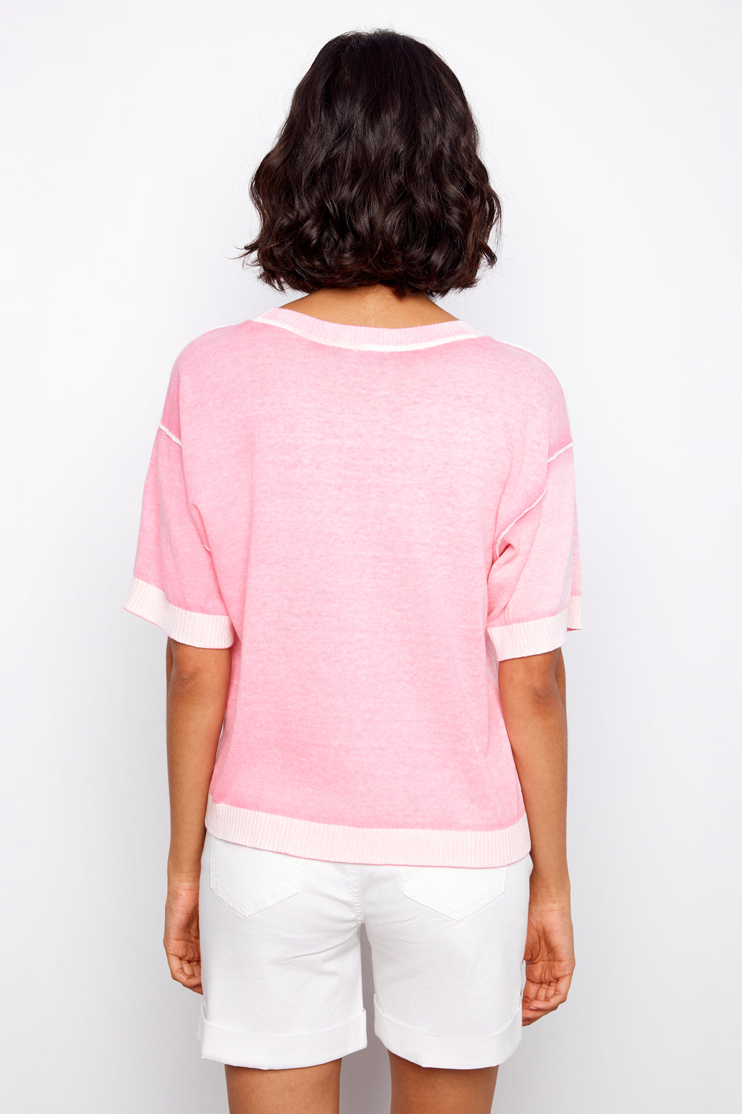 Person wearing a pink top and white shorts on a plain background
