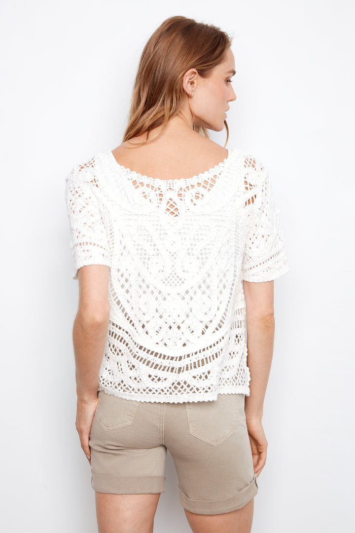 Woman wearing a white lace top and beige shorts on a white background