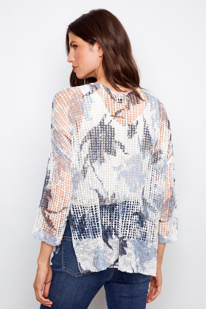 Woman wearing a sheer floral blouse with a white background