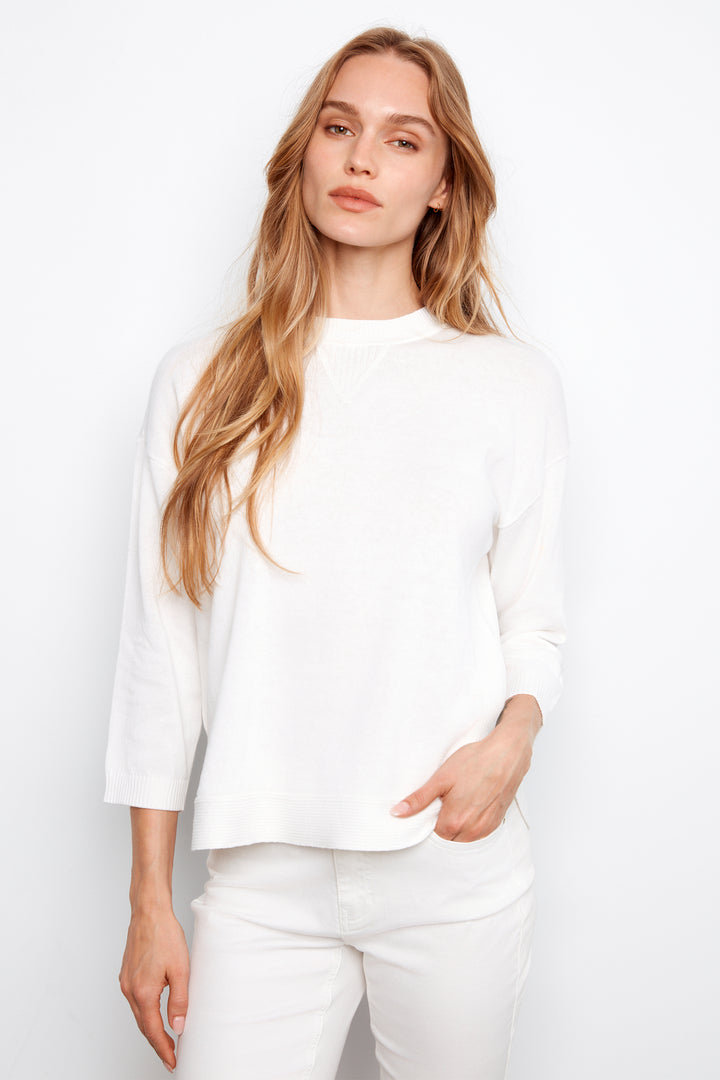 Woman wearing a white sweater against a plain background