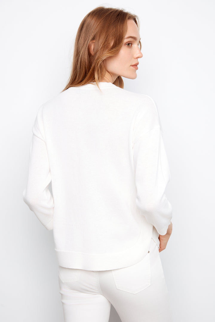 Woman wearing a white sweater against a plain background
