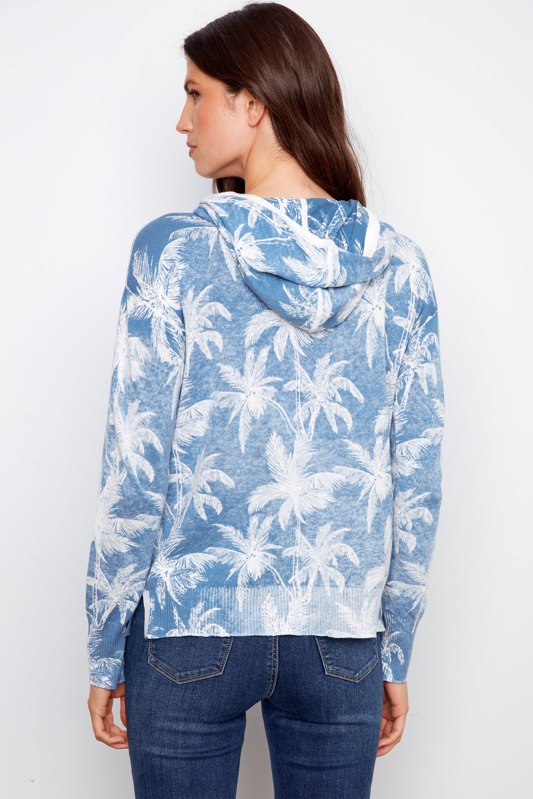 Woman wearing a blue hoodie with palm tree pattern on a white background