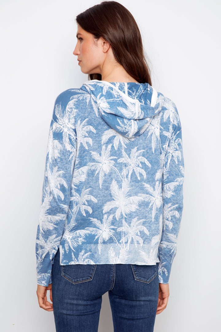 Woman wearing a blue hoodie with palm tree pattern on a white background