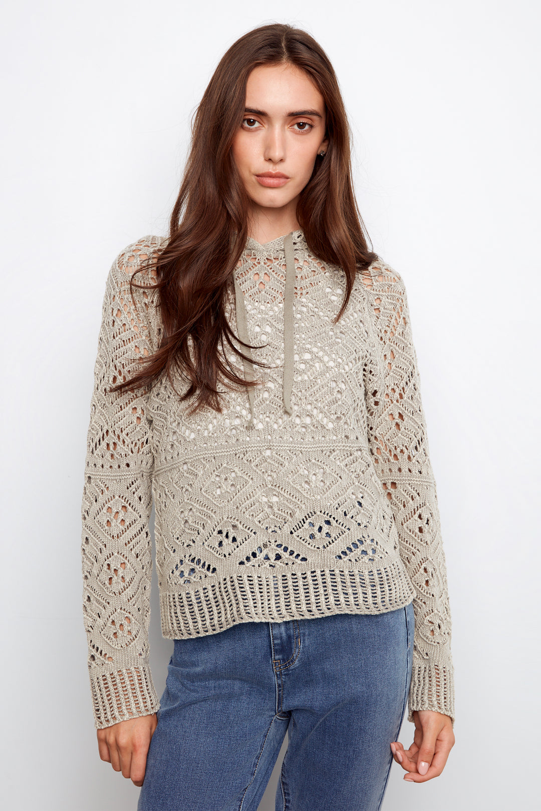 Woman wearing a beige lace sweater and blue jeans on a white background
