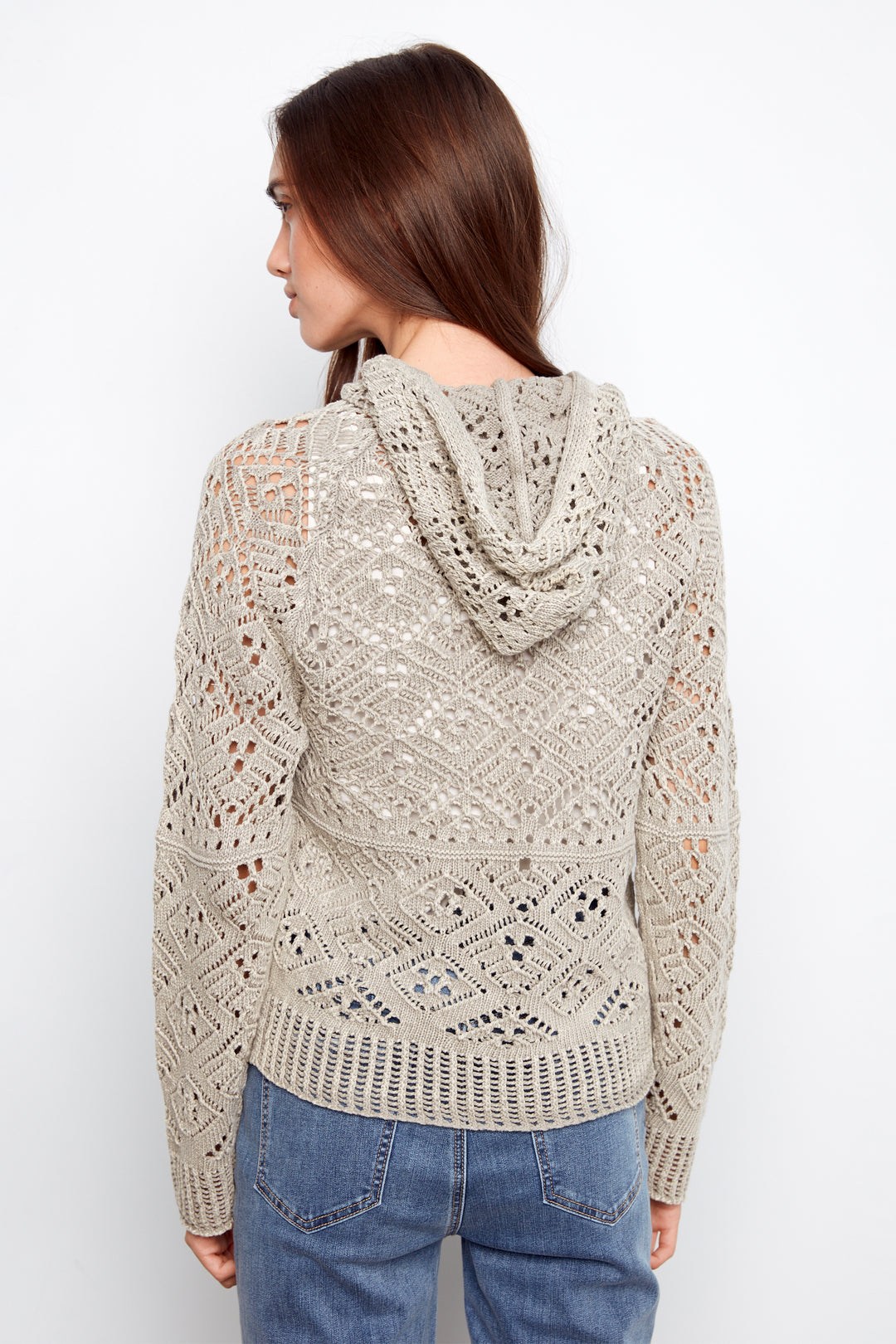 Woman wearing a beige lace-patterned hoodie against a white background