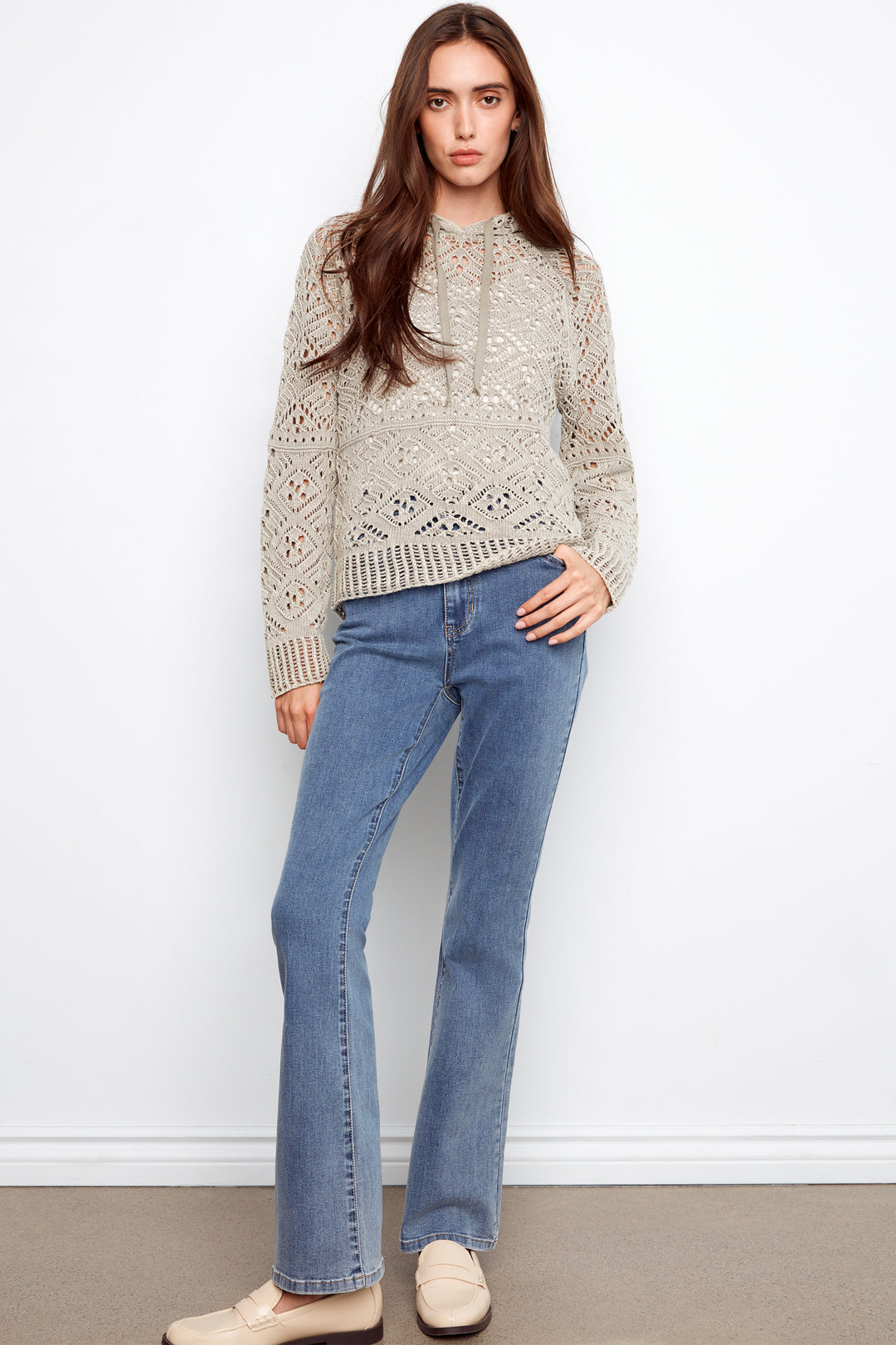 Woman wearing a patterned sweater and blue jeans against a white background