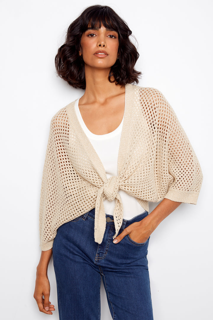 Woman wearing a beige knit cardigan front tie twist over a white top and blue jeans on a white background