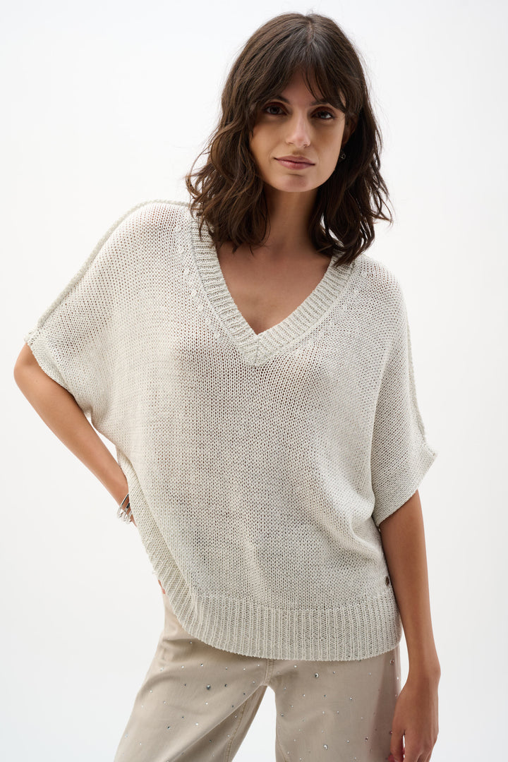 Woman wearing a light gray knit sweater against a white background