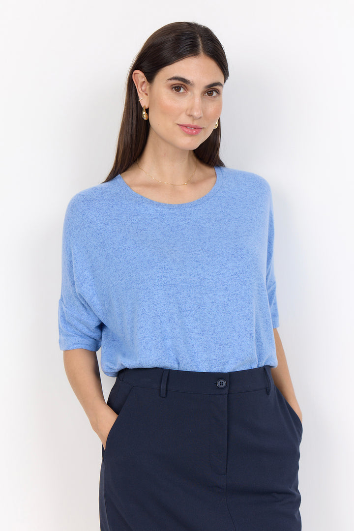 Woman wearing a blue top and navy pants against a white background