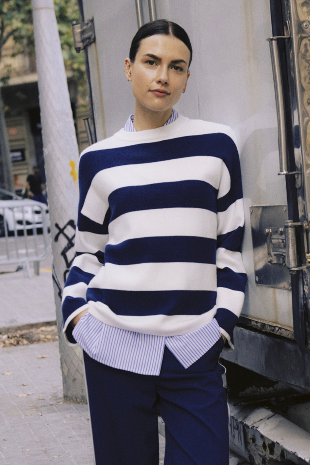 Person wearing a blue and white striped sweater on a city street.