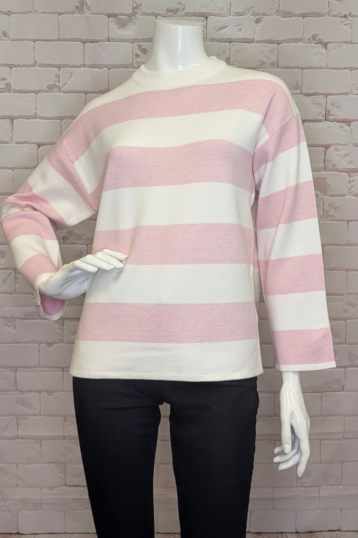 Mannequin wearing a pink and white striped sweater with black pants against a textured wall.