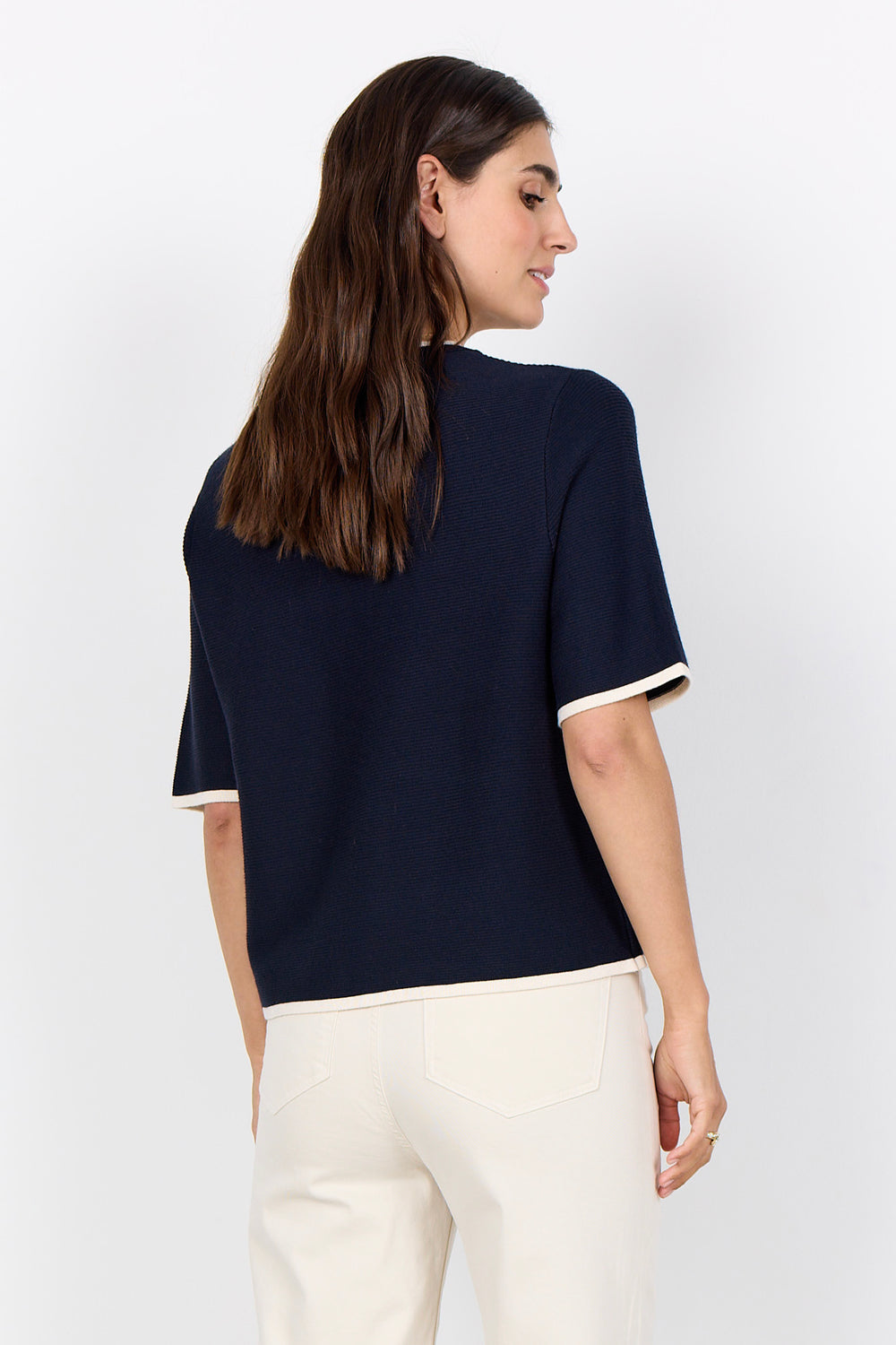 Woman wearing a navy blue top with white trim on a white background