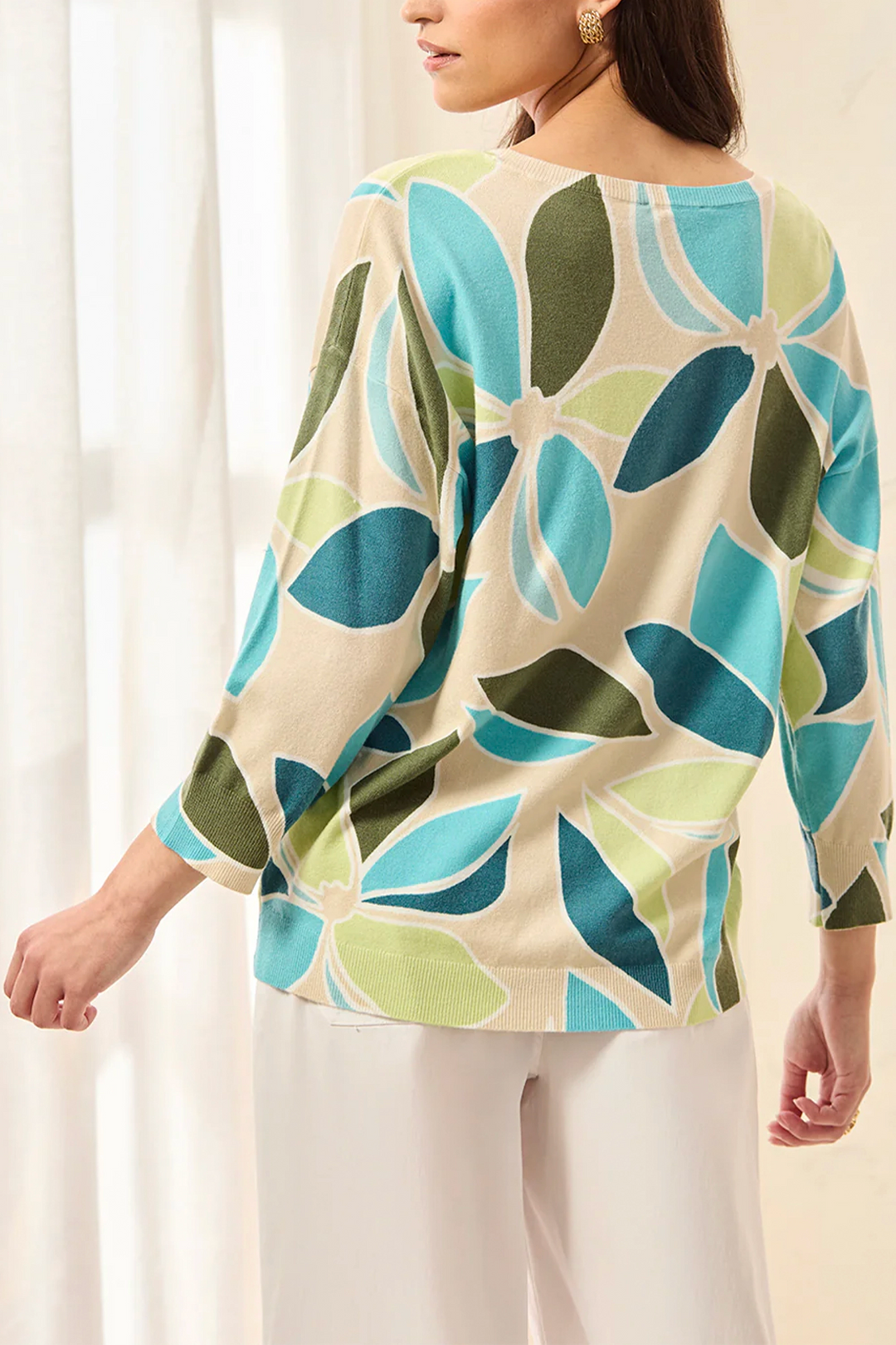 Woman wearing a colorful patterned top with a plain background