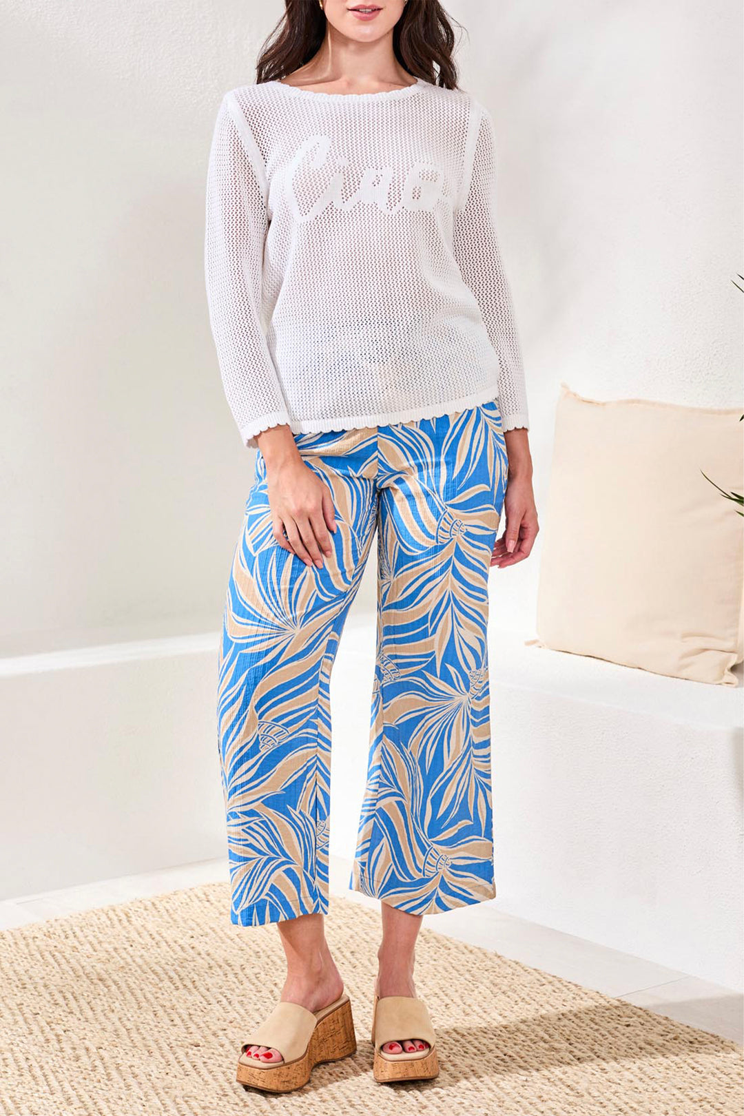 Woman wearing a white sweater and blue patterned pants on a white background