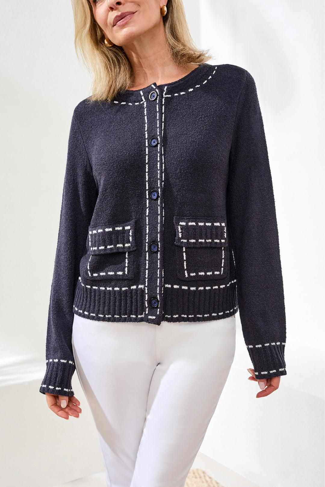 Woman wearing a navy blue cardigan with white stitching on a white background