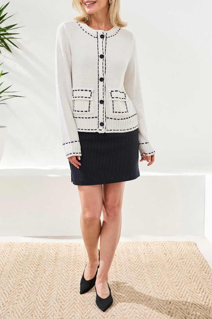 Woman wearing a white patterned cardigan over a black skirt with a white background