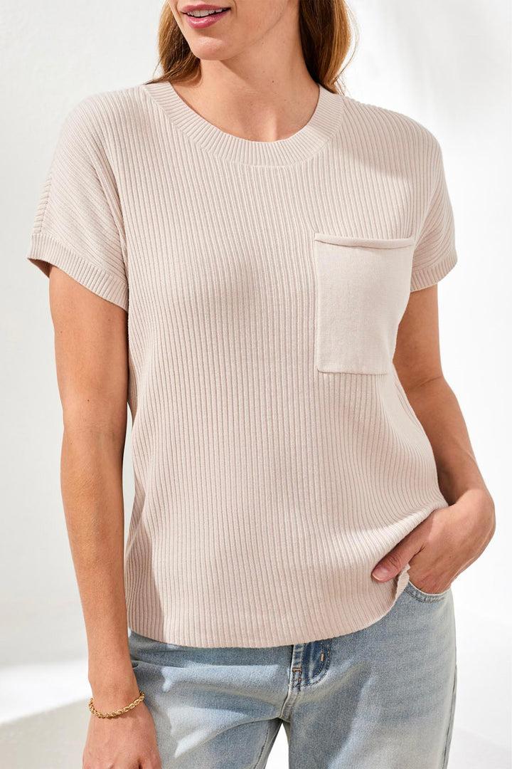 Woman wearing a beige ribbed top with a pocket and light blue jeans on a white background