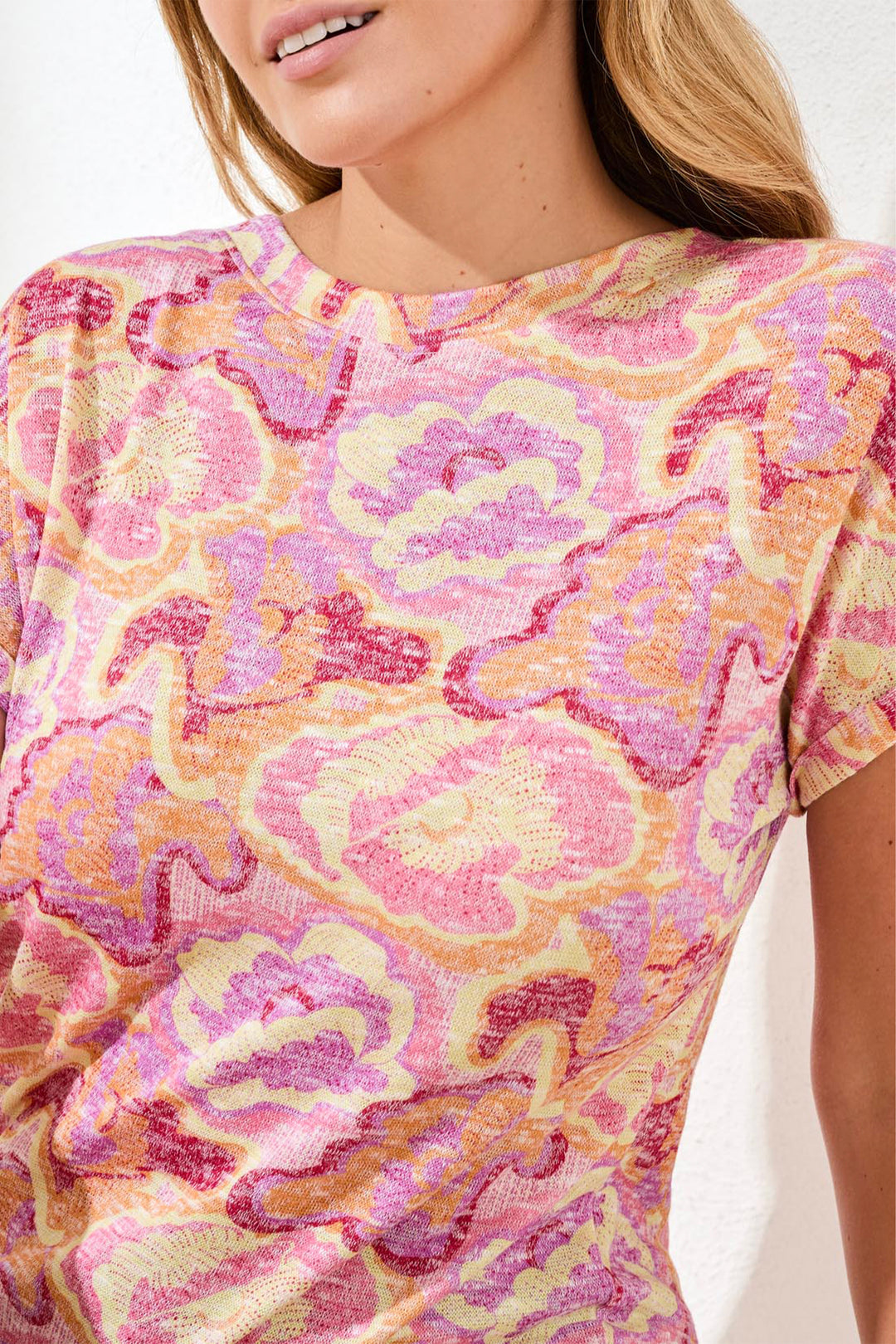 Woman wearing a pink and yellow patterned top against a white background