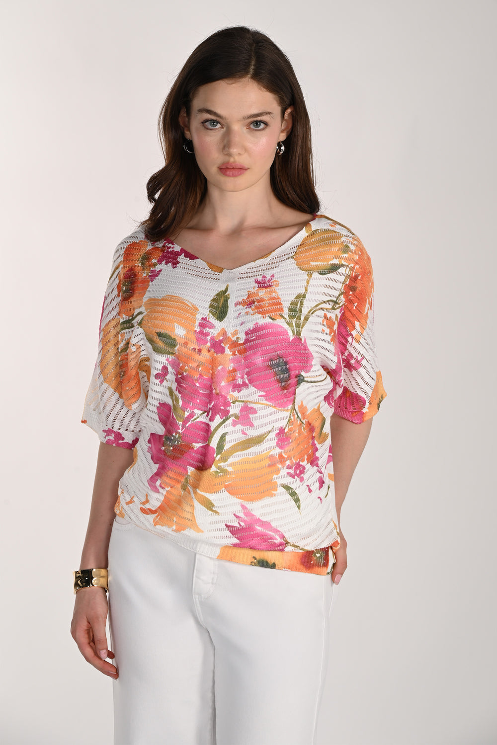 Woman wearing a colorful floral sweater top against a white background