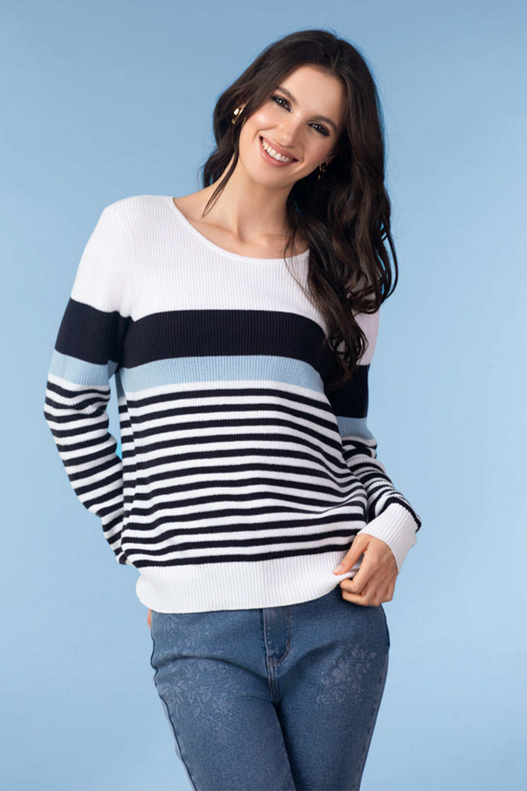 Woman wearing a striped sweater and jeans against a blue background