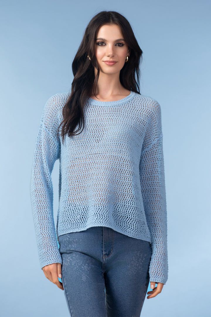 Woman wearing a light blue knitted sweater against a plain background