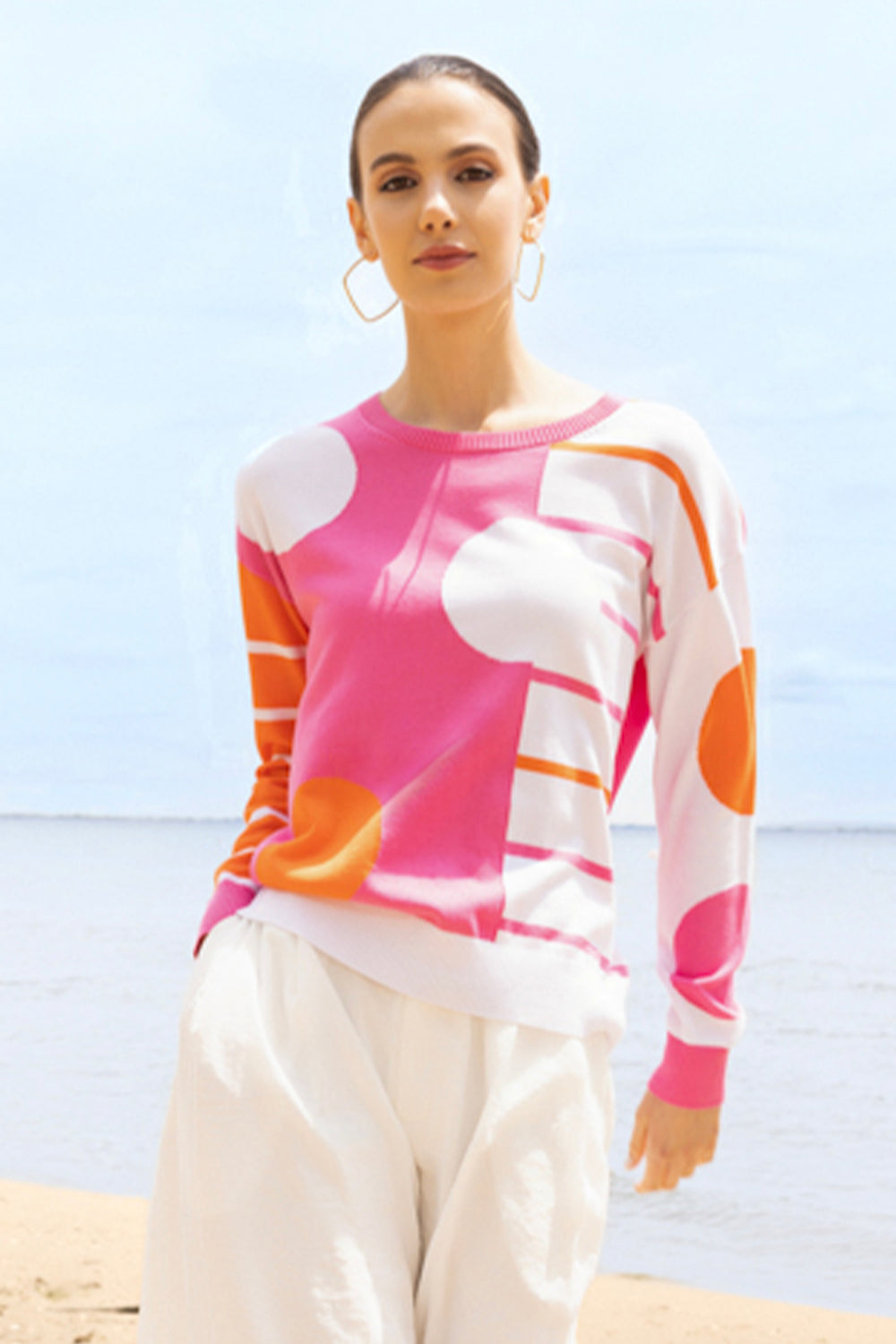 Woman wearing a colorful polka dot sweater with a beach background