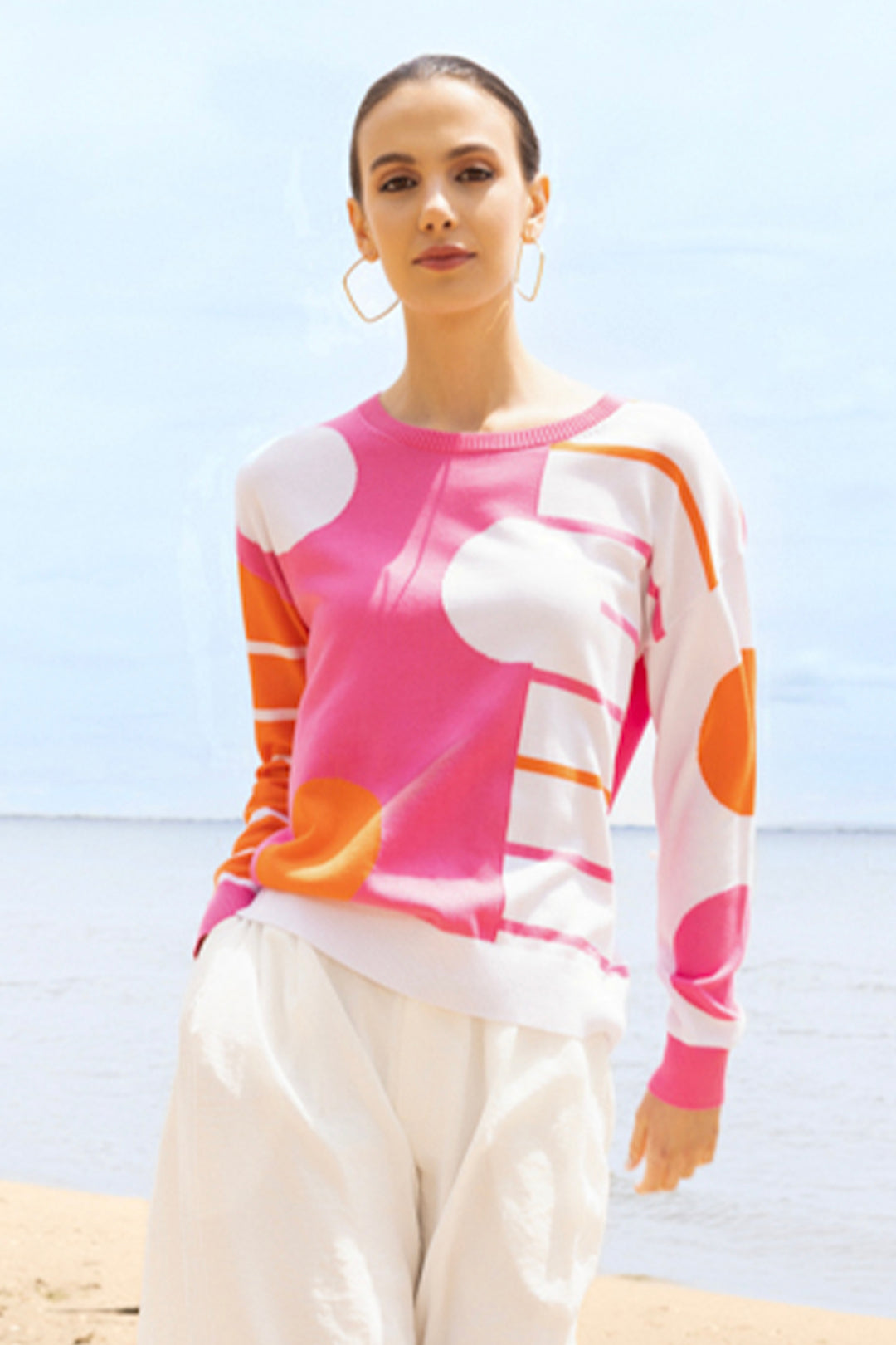 Woman wearing a colorful polka dot sweater with a beach background