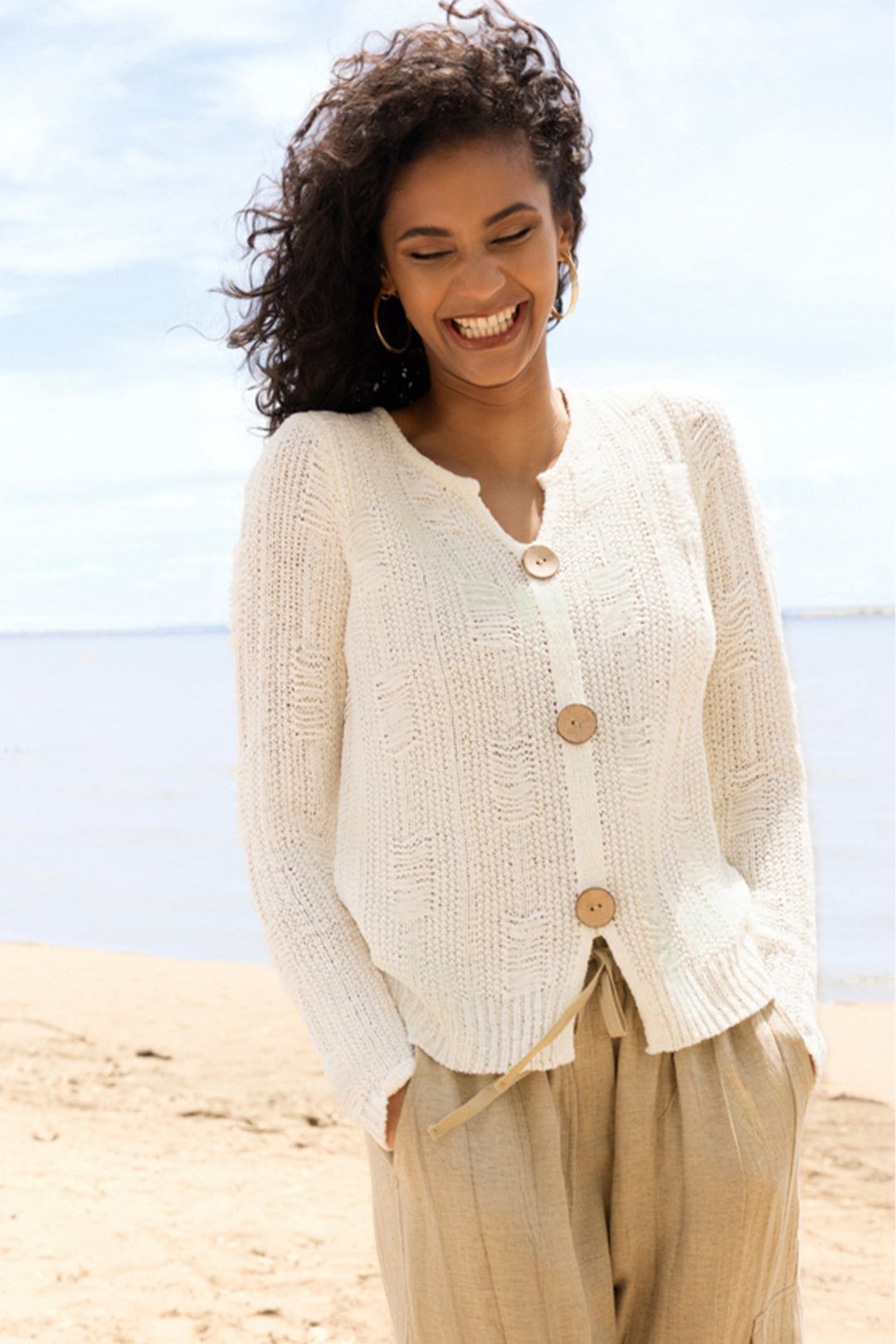 Woman wearing a white button cardigan on a beach