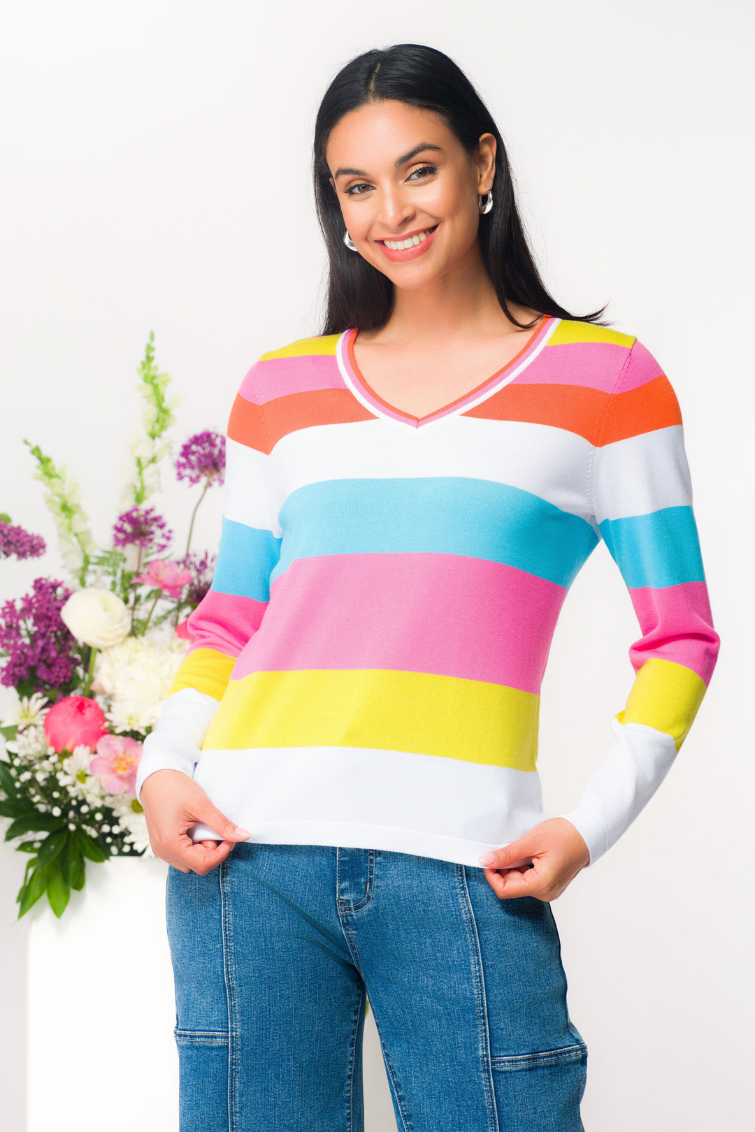 Woman wearing a colorful striped sweater with flowers in the background